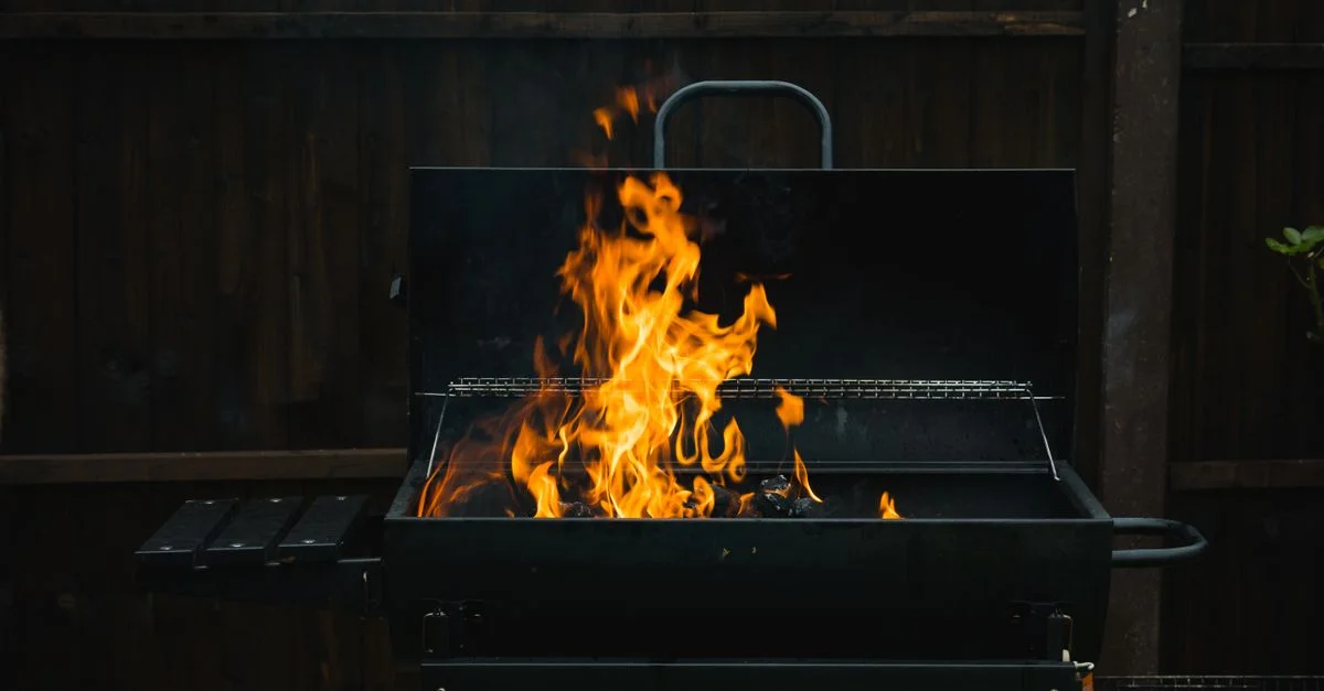 Un gros plan sur un barbecue en plein air avec des flammes ardentes sur du charbon, parfait pour les grillades d'été.
