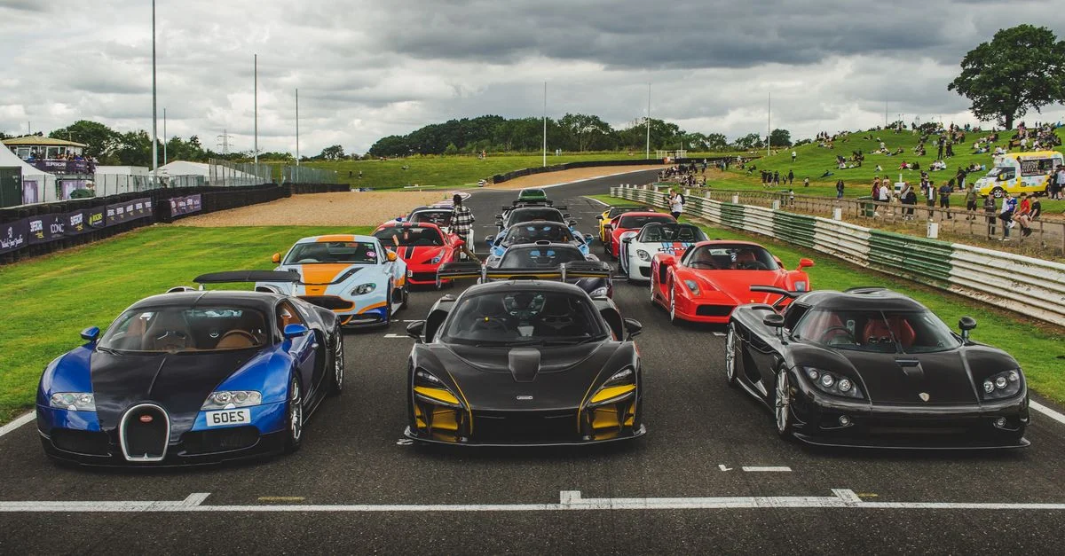 Une collection de voitures de sport de luxe prêtes pour un événement de course sur une piste extérieure.