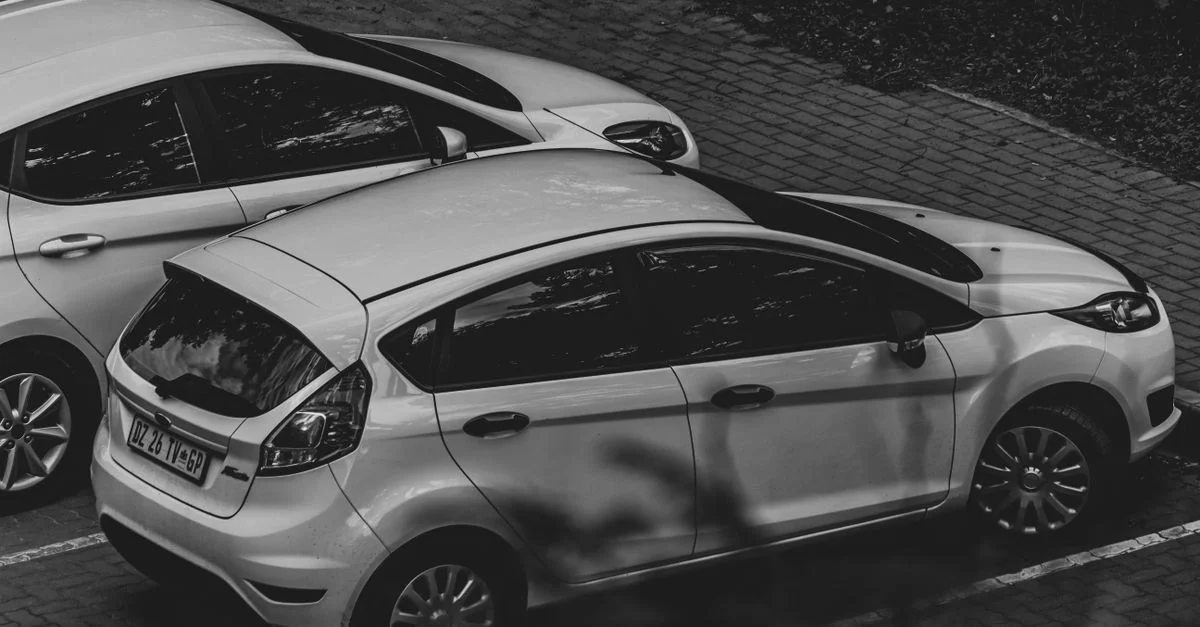Une image monochrome mettant en avant des voitures garées dans un environnement urbain.