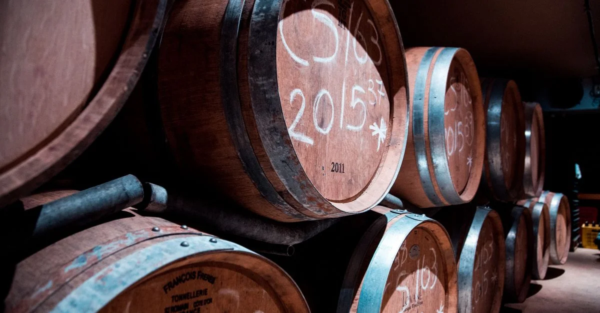 Une cave faiblement éclairée à Stellenbosch, en Afrique du Sud, présentant des fûts en bois de vin empilés.