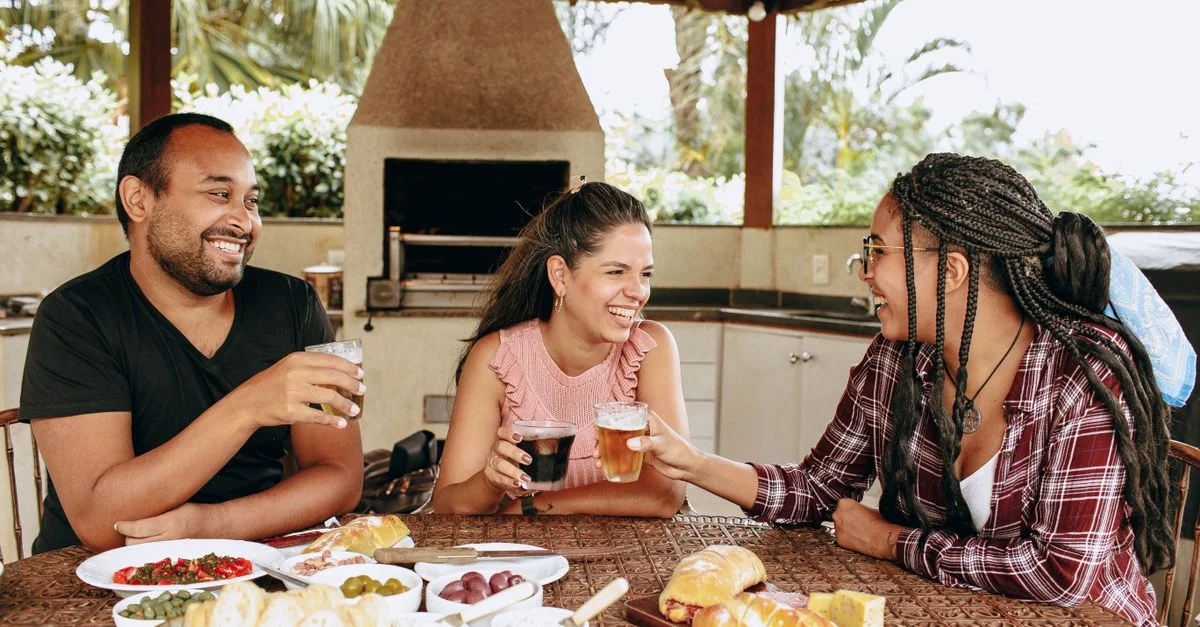 Trois amis partageant un repas joyeux en plein air, renforçant la camaraderie et l'unité.