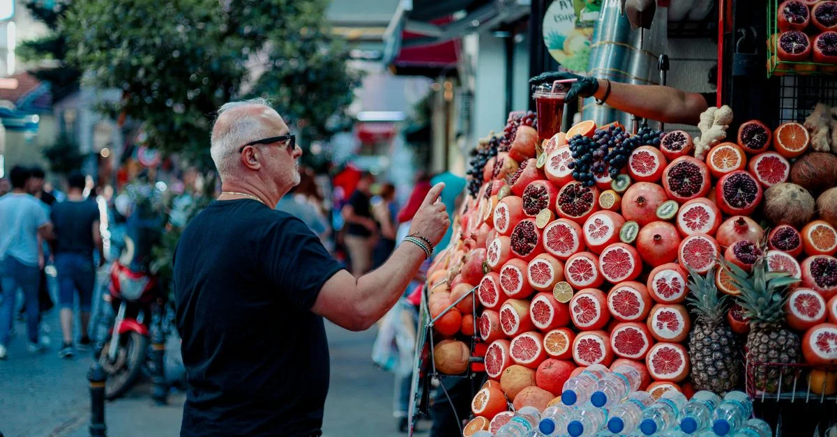 Un homme adulte parcourant un stand de marché coloré rempli de fruits frais dans une rue animée.